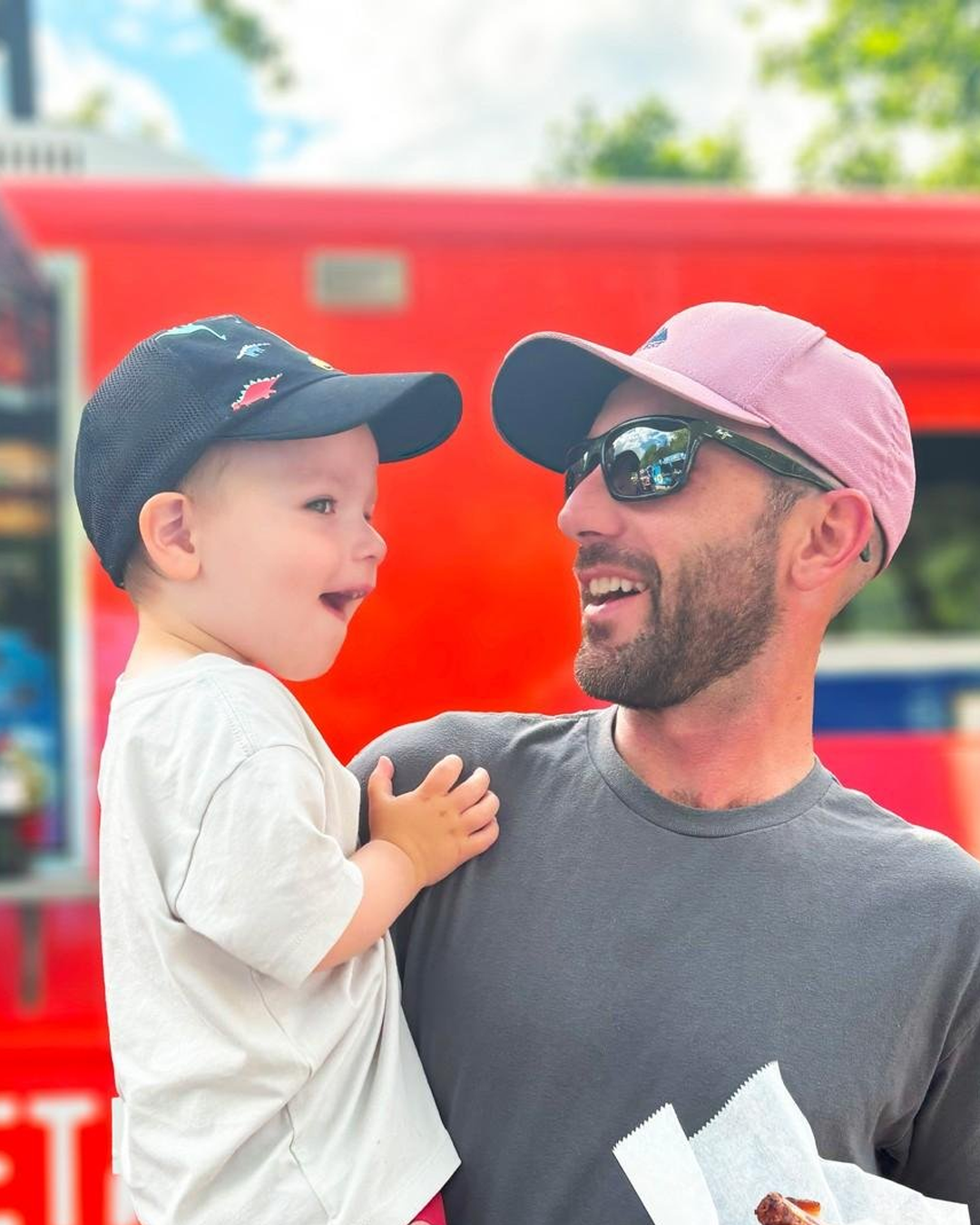 Father holding son in front of a food truck in highland park